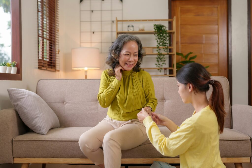 Asian caregiver or daughter takes care of the elderly at home in the living room to squeeze a gentle