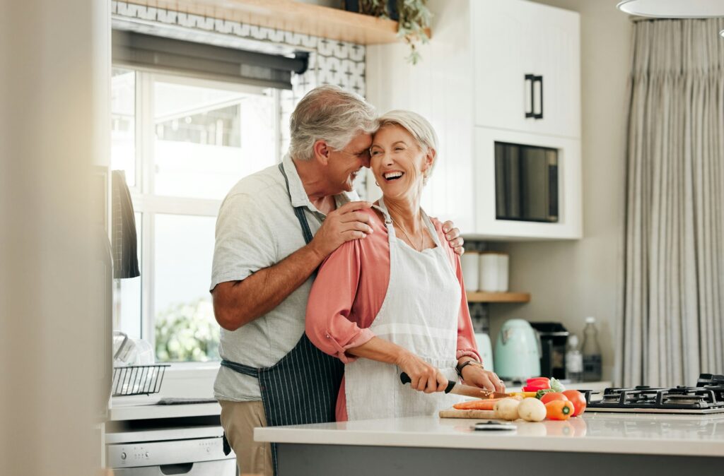 Senior couple in kitchen, cooking healthy food together and happy in retirement lifestyle. Elderly